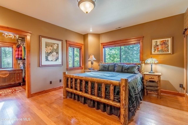 bedroom with multiple windows, baseboards, and light wood-type flooring