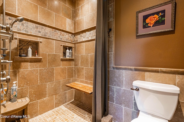 full bathroom featuring a wainscoted wall, toilet, tile walls, and a stall shower