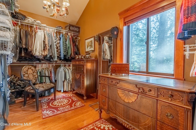 walk in closet featuring lofted ceiling, light wood-style flooring, and a chandelier