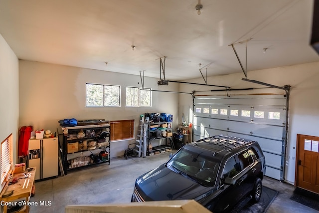 garage with a garage door opener and white fridge with ice dispenser