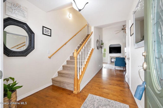 foyer with stairs, a ceiling fan, and wood finished floors