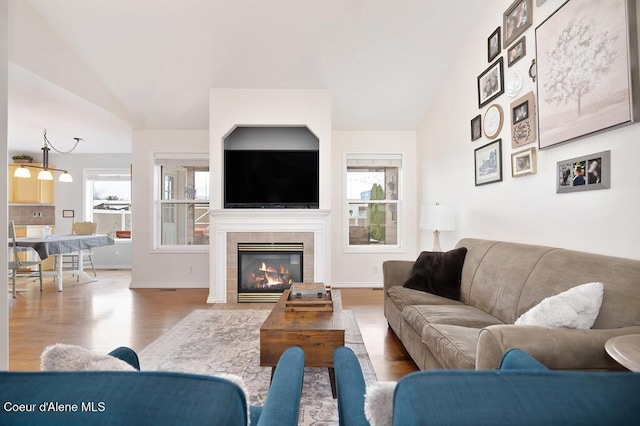 living room featuring lofted ceiling, wood finished floors, and a tile fireplace