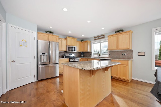 kitchen featuring light wood-style flooring, light brown cabinets, backsplash, and stainless steel appliances