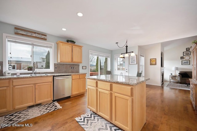 kitchen featuring a sink, dishwasher, wood finished floors, and light brown cabinets