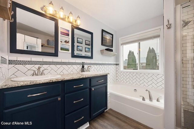 full bath with a sink, a garden tub, wood finished floors, and double vanity