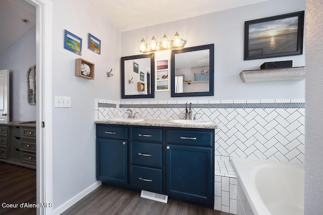 bathroom featuring a sink, visible vents, wood finished floors, and double vanity