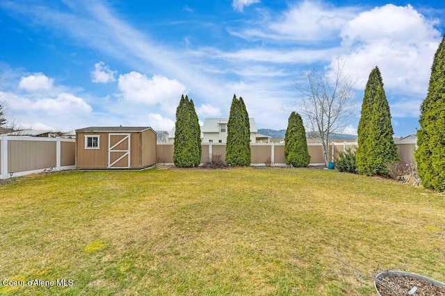 view of yard featuring an outdoor structure, a fenced backyard, and a shed