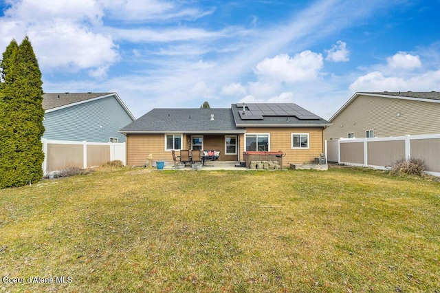 back of property featuring a patio area, solar panels, a yard, and a fenced backyard