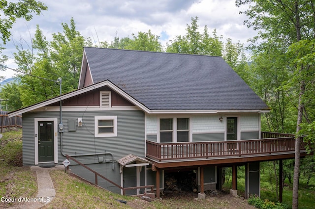 back of house with a deck and roof with shingles