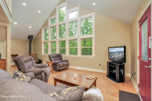 living room with light wood finished floors, baseboards, recessed lighting, a wood stove, and high vaulted ceiling