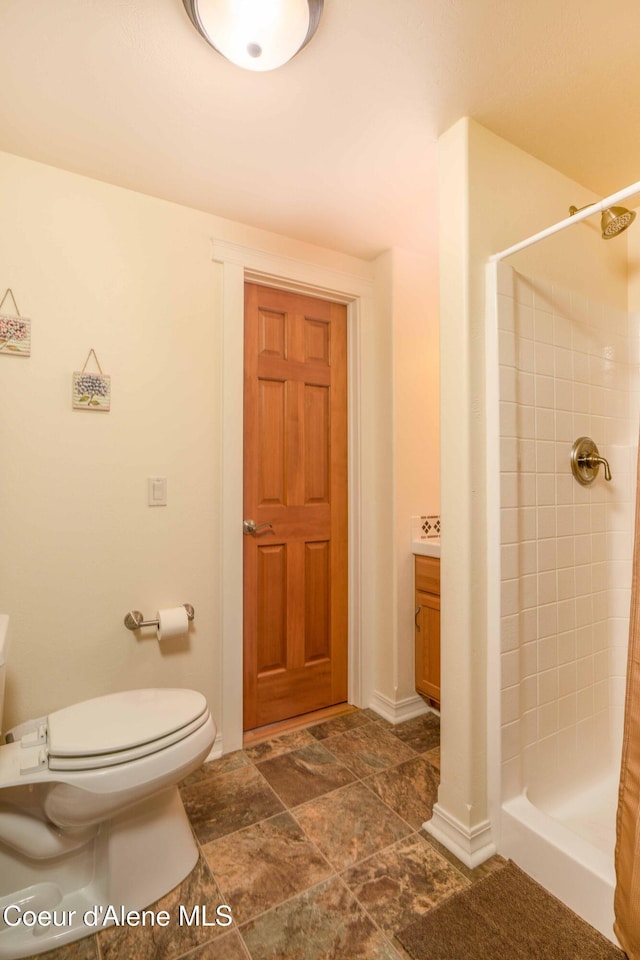 bathroom with a shower stall, toilet, and stone finish floor