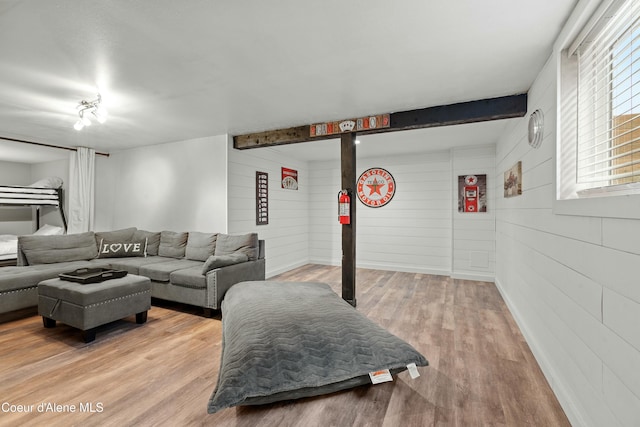 living area featuring beam ceiling and wood finished floors