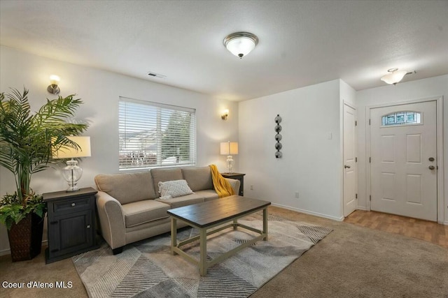 living area featuring visible vents, light carpet, and baseboards