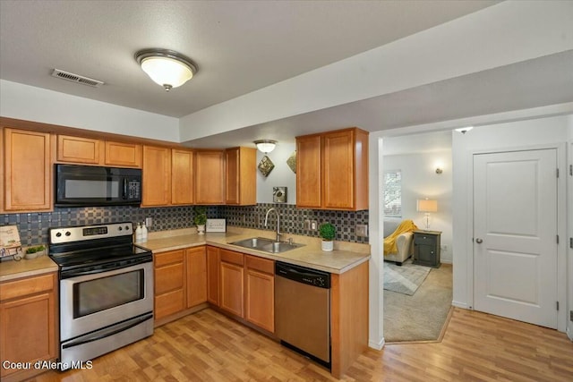 kitchen featuring visible vents, a sink, tasteful backsplash, appliances with stainless steel finishes, and light countertops