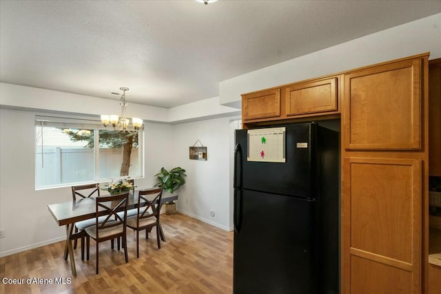 dining space featuring light wood-style flooring, a notable chandelier, baseboards, and a textured ceiling