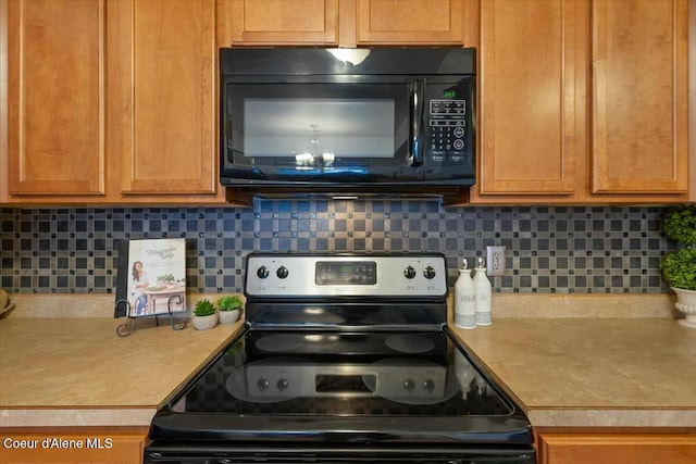 kitchen featuring tasteful backsplash, light countertops, black microwave, and electric stove