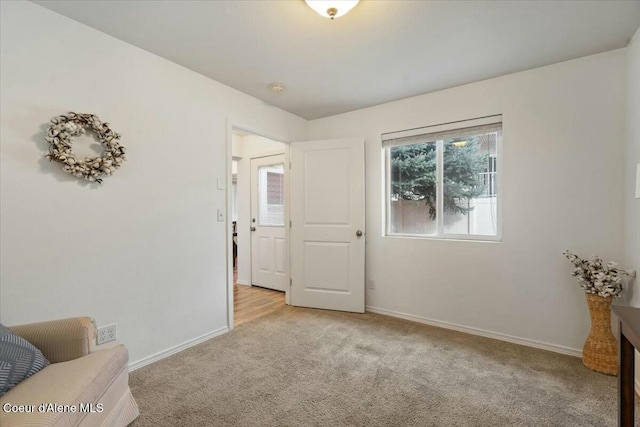 sitting room featuring light colored carpet and baseboards