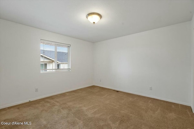 carpeted spare room featuring visible vents and baseboards