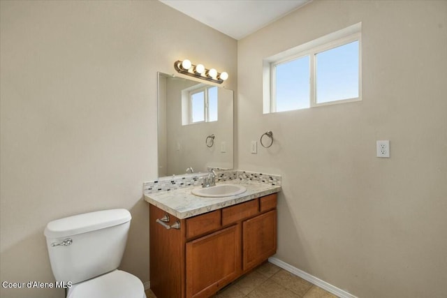 bathroom with toilet, vanity, and baseboards