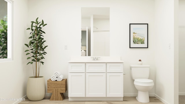 bathroom featuring toilet, vanity, and baseboards