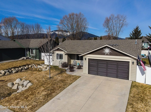 ranch-style house with fence, driveway, an attached garage, a shingled roof, and a mountain view