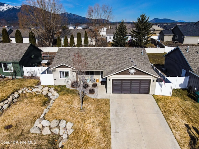 view of front of property with a mountain view, an attached garage, and a fenced backyard