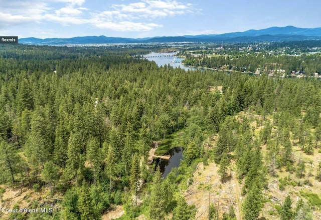 drone / aerial view with a forest view and a water and mountain view