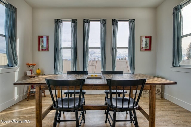 dining area with light wood-type flooring and baseboards