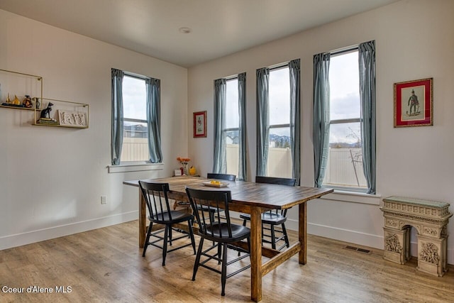 dining area with a wealth of natural light, baseboards, and light wood finished floors