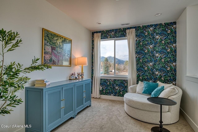 sitting room featuring a mountain view, baseboards, and light carpet