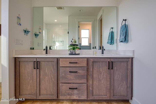 bathroom with a sink, a shower, and double vanity