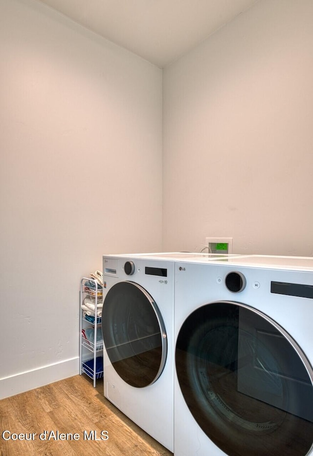 washroom with laundry area, wood finished floors, baseboards, and washer and clothes dryer