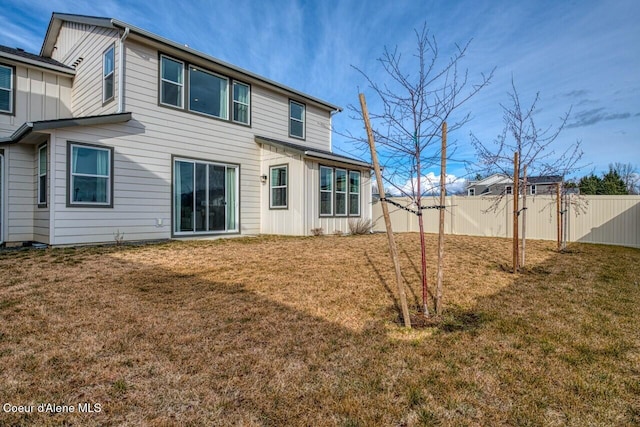 rear view of house featuring a yard, fence, and board and batten siding