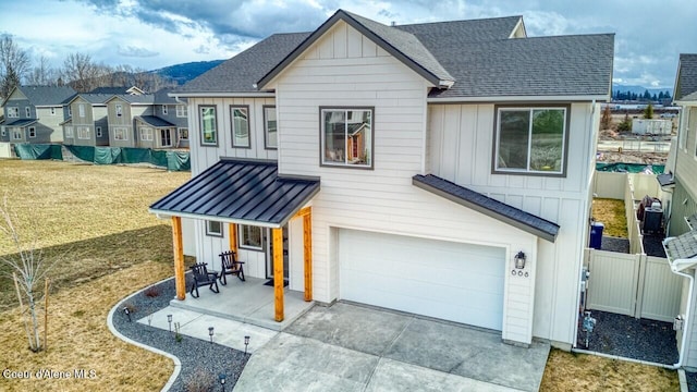 view of front of property featuring board and batten siding, an attached garage, fence, and a shingled roof