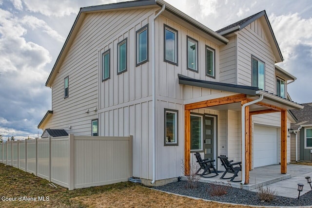 exterior space featuring driveway, board and batten siding, an attached garage, and fence