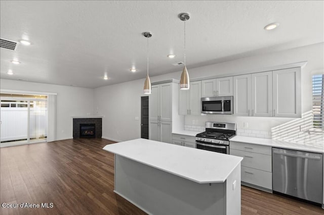 kitchen with visible vents, dark wood finished floors, stainless steel appliances, light countertops, and a center island