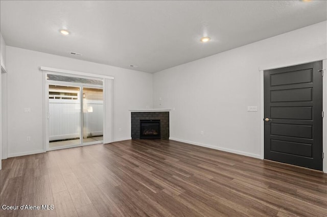 unfurnished living room with visible vents, a brick fireplace, baseboards, recessed lighting, and wood finished floors