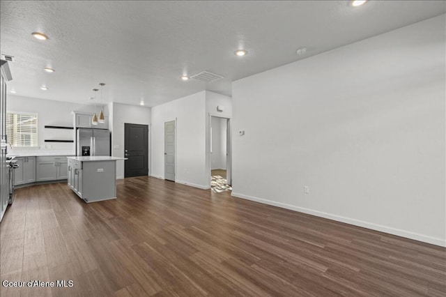 kitchen featuring a kitchen island, dark wood finished floors, stainless steel fridge with ice dispenser, light countertops, and open floor plan