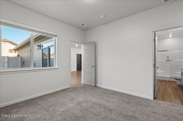 unfurnished bedroom with visible vents, baseboards, carpet, and ensuite bath