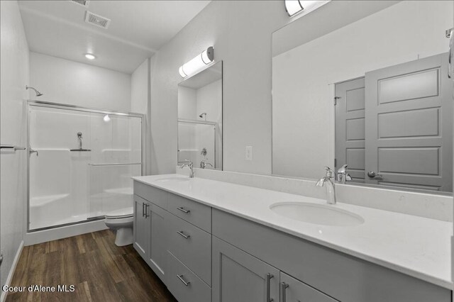 bathroom with visible vents, a stall shower, wood finished floors, and a sink