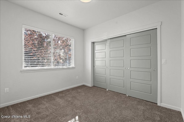 unfurnished bedroom with baseboards, a closet, carpet floors, and visible vents