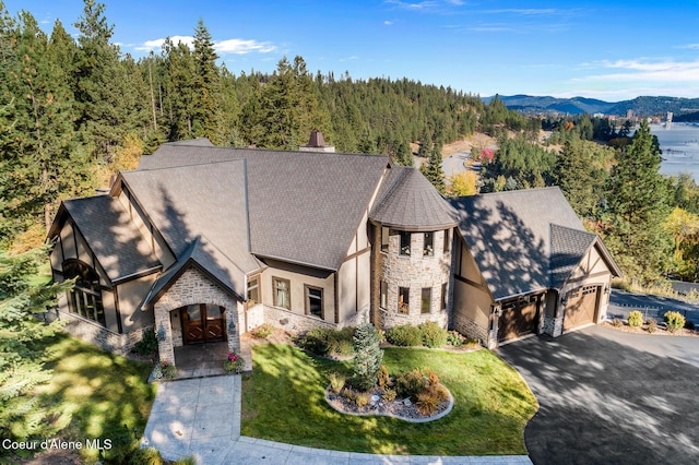 view of front of home with a front yard, driveway, stucco siding, a garage, and stone siding