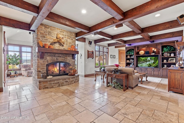 living room with stone tile floors, beamed ceiling, and baseboards