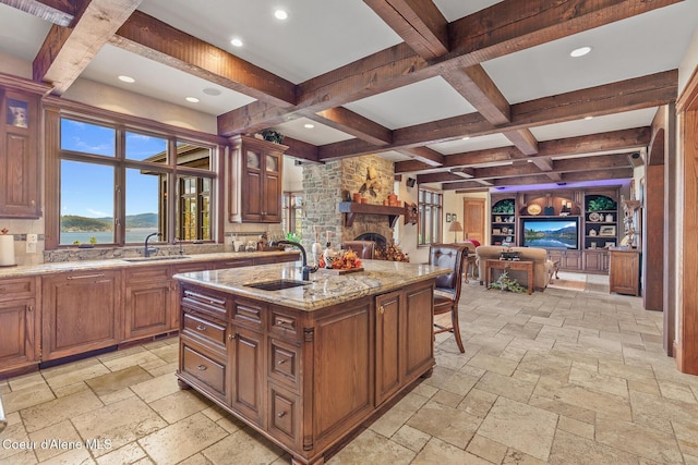 kitchen featuring stone tile flooring, open floor plan, coffered ceiling, and a sink