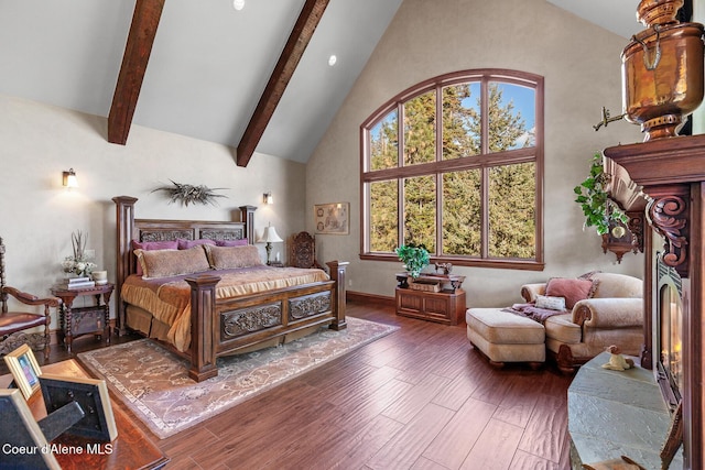 bedroom with beam ceiling, wood finished floors, and high vaulted ceiling