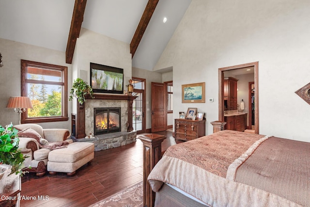 bedroom featuring connected bathroom, beam ceiling, a stone fireplace, wood finished floors, and high vaulted ceiling