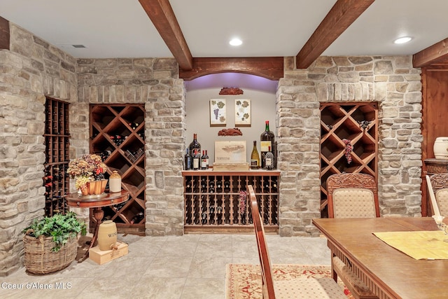 wine room with beam ceiling and tile patterned flooring