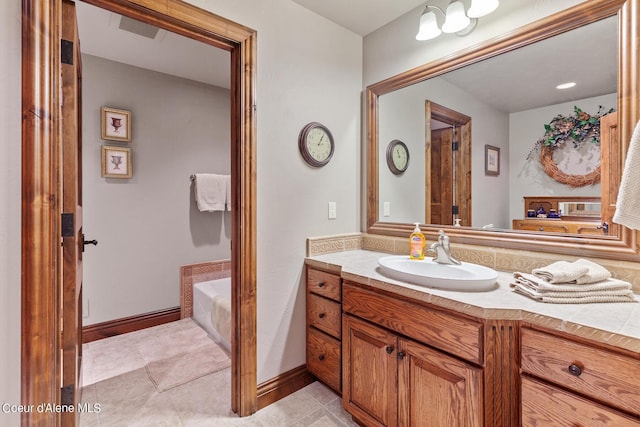 bathroom with baseboards, tile patterned floors, vanity, and a garden tub