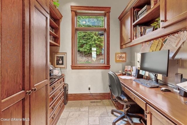 office area with baseboards and stone tile flooring