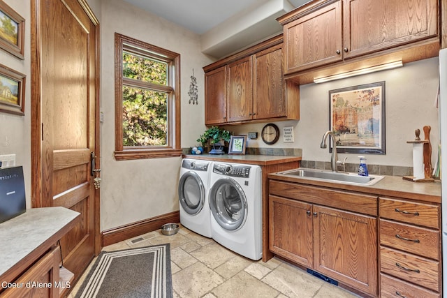 clothes washing area with visible vents, washer and clothes dryer, stone tile flooring, cabinet space, and a sink